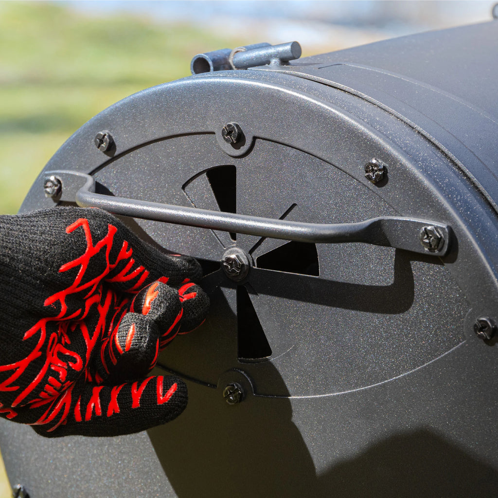 Someone wearing a heat-resistant glove opens the slide of the damper in the left side of the grill.