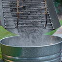 Someone dumps cool ashes from an EasyDump ash tray into a metal bucket